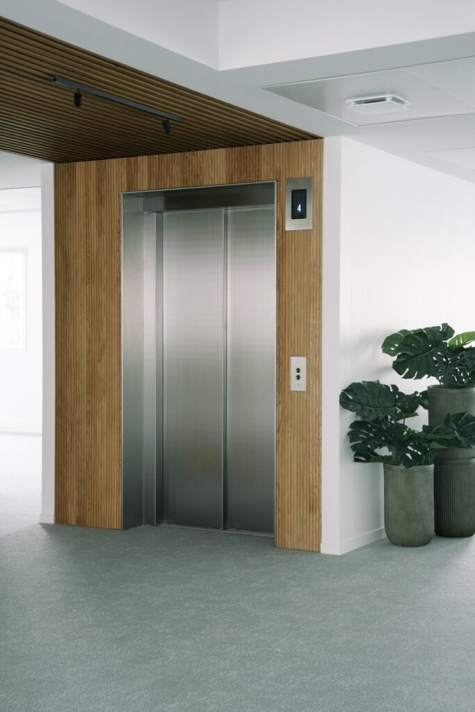 Zona del ascensor en Coworking Hiptown con revestimientos de madera Spigoplank por Spigogroup